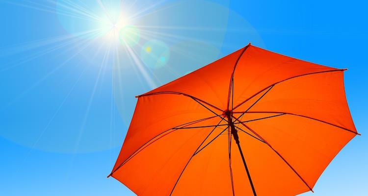 Geöffneter orangefarbiger Regenschirm. Im Hintergrund blauher Himmel mit strahlender Sonne