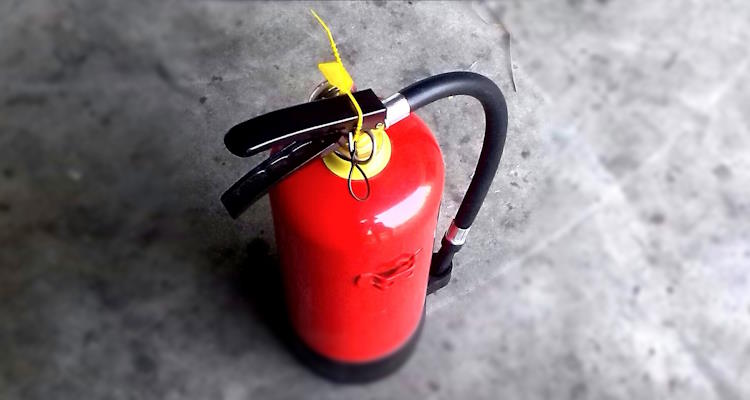 Ein Feuerlöscher steht auf grauem Boden