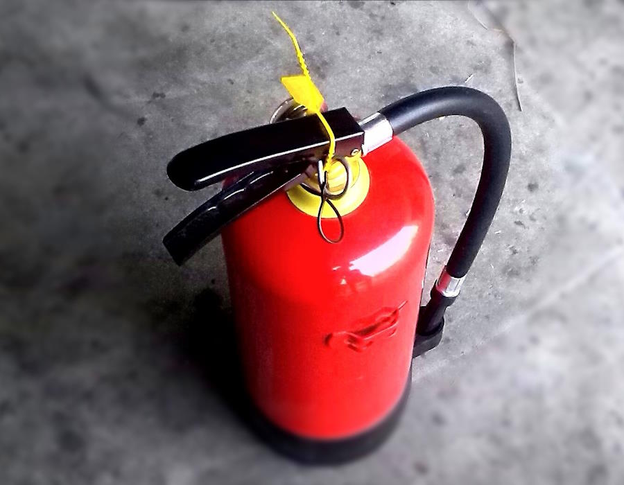 Ein Feuerlöscher steht auf grauem Boden