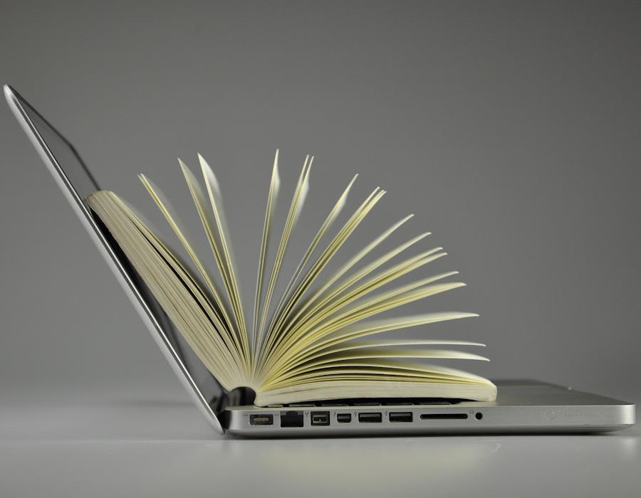 Ein aufgeklappter Laptop in der Seitenansicht. Auf der Tatstatur liegt ein aufgeschlagenes Buch. Ein aufgeklappter Laptop in der Seitenansicht. Auf der Tatstatur liegt ein aufgeschlagenes Buch.