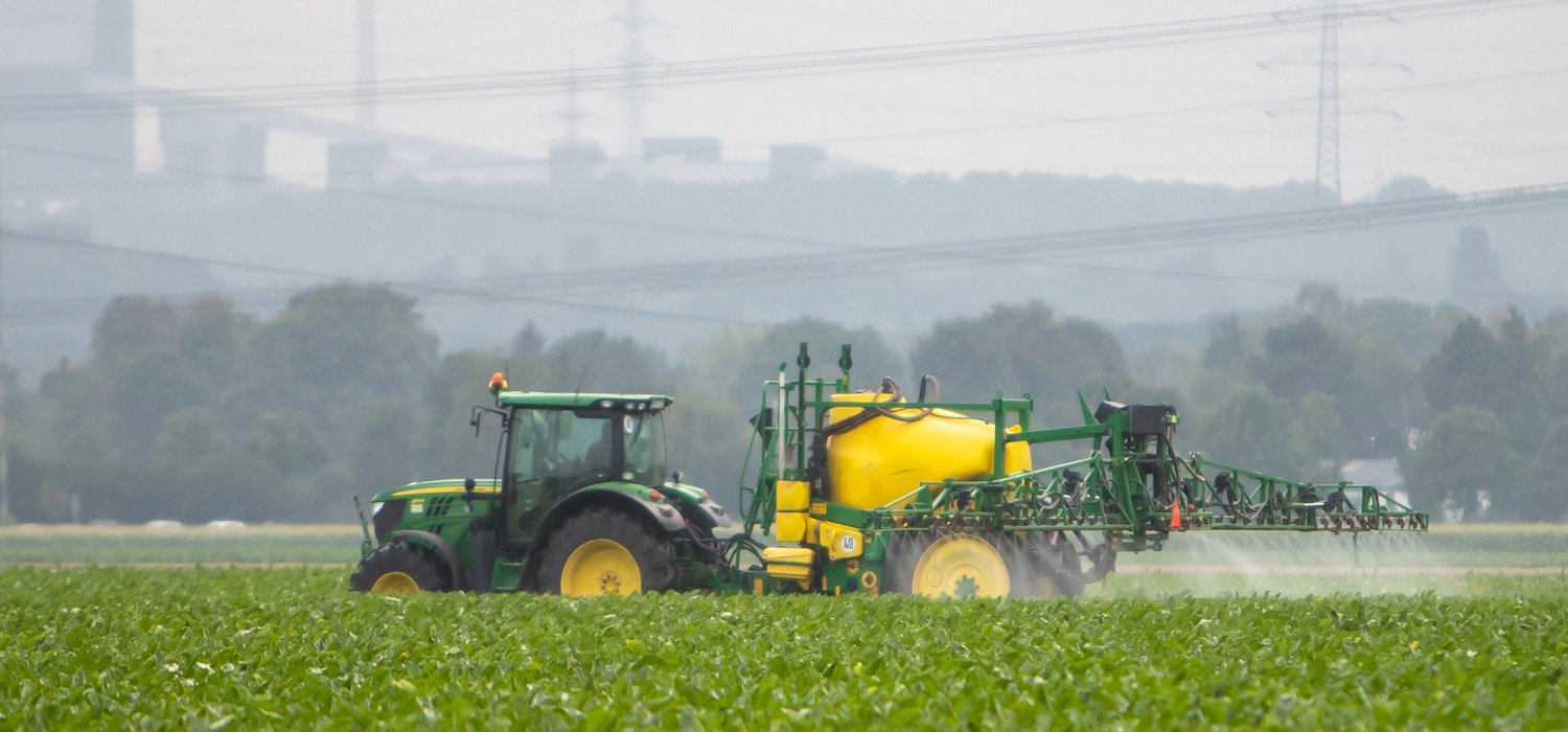 Traktor mit Anhängefeldspritze in Aktion auf einem Zuckerrübenfeld bei Hürth