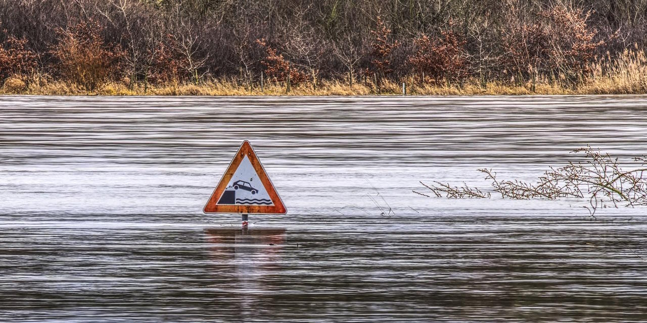 Hochwasser eines Flusses. Ein Straßenschild ragt aus dem Wasser hervor Hochwasser eines Flusses. Ein Straßenschild ragt aus dem Wasser hervor