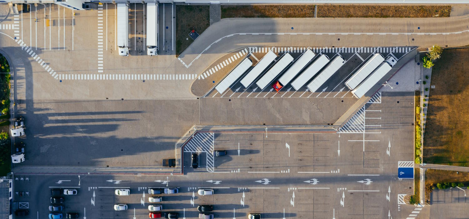 Symbolbild: Luftaufnahme eines Speditionsgeländes, ein großer asphaltierter Parplatz mit parkenden LKW. Symbolbild: Luftaufnahme eines Speditionsgeländes, ein großer asphaltierter Parplatz mit parkenden LKW.